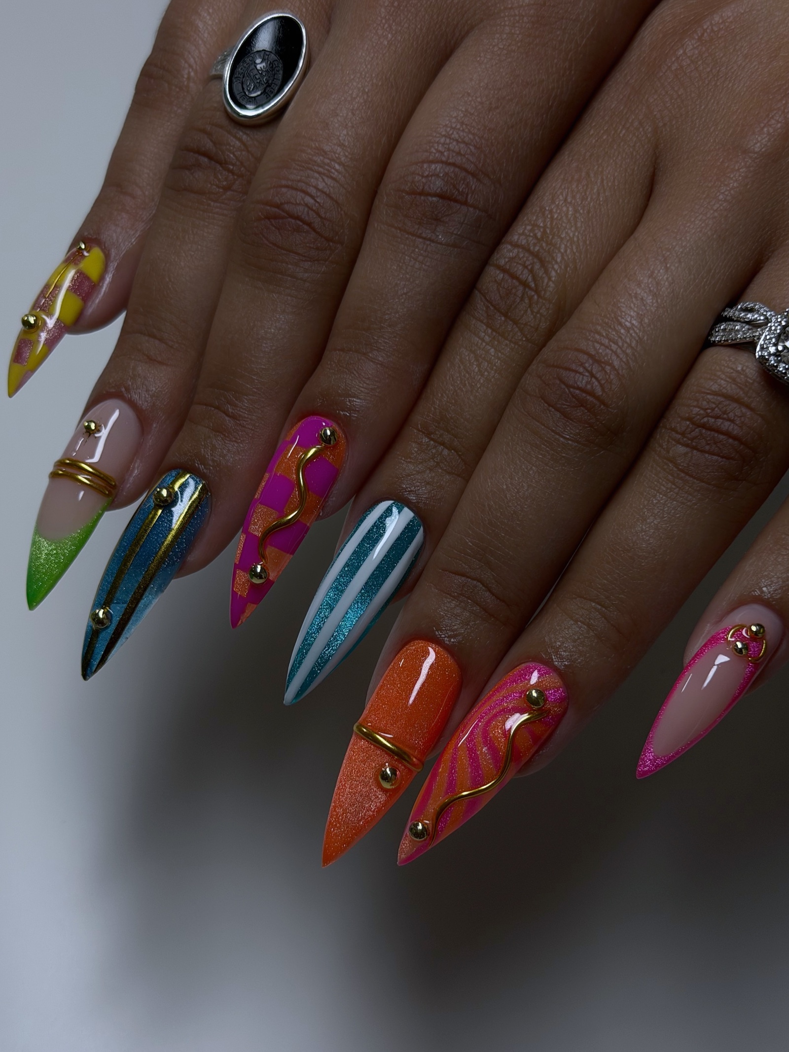 Pink cat-eye almond nails dotted with crystals, worn with gold rings